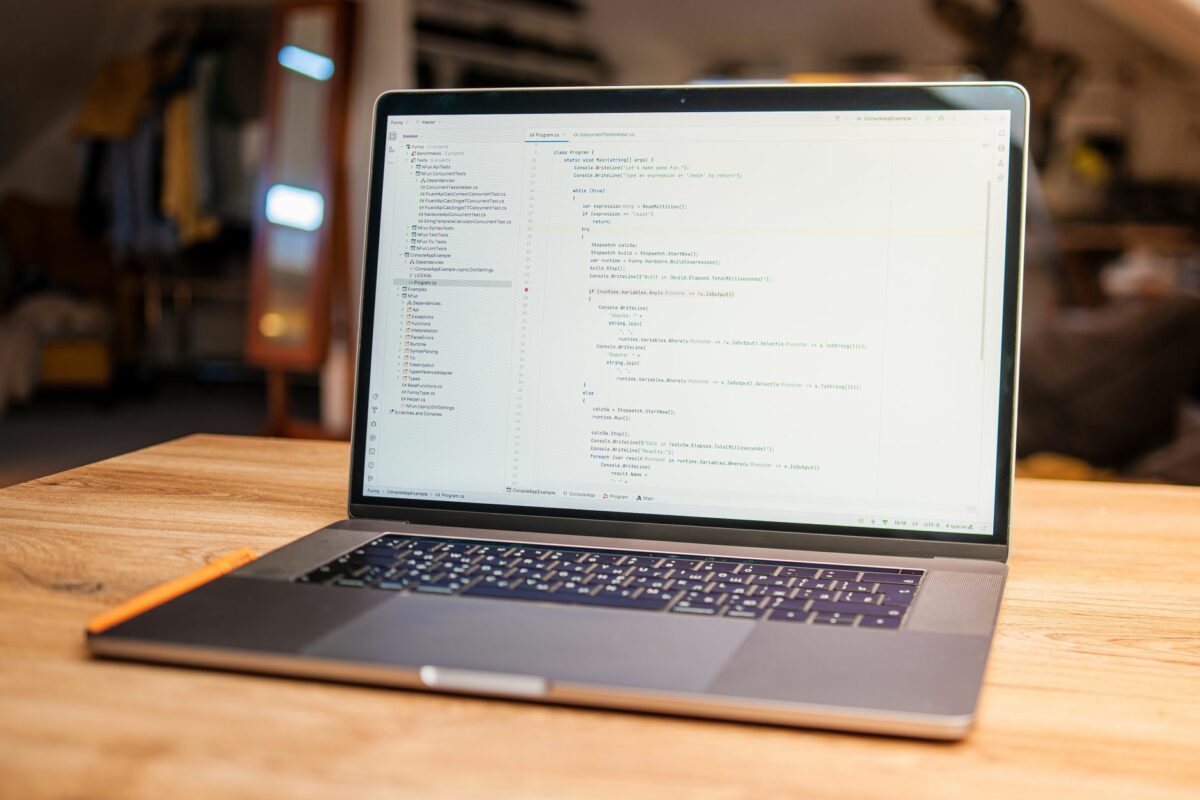 Ordinateur portable affichant du code sur un bureau en bois, lors de la création d'un site internet
